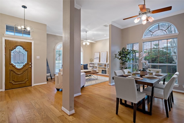 dining area featuring ornamental molding, a healthy amount of sunlight, ceiling fan with notable chandelier, and light hardwood / wood-style flooring