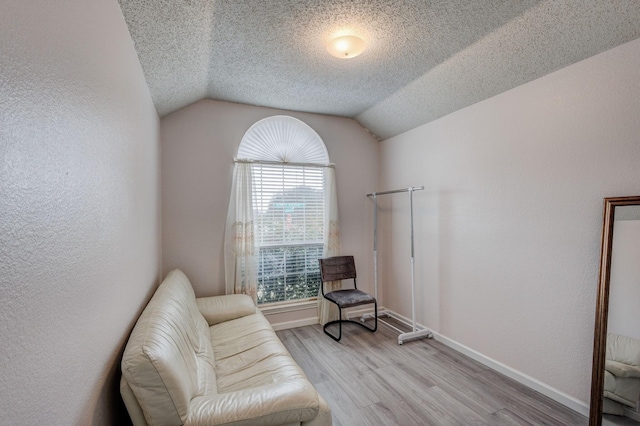 sitting room featuring vaulted ceiling, light hardwood / wood-style floors, and a textured ceiling