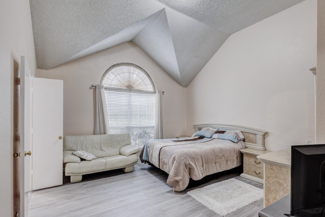 bedroom featuring lofted ceiling, a textured ceiling, and light wood-type flooring