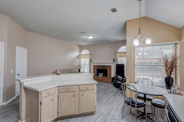 kitchen featuring light hardwood / wood-style flooring, hanging light fixtures, a center island, light brown cabinetry, and vaulted ceiling