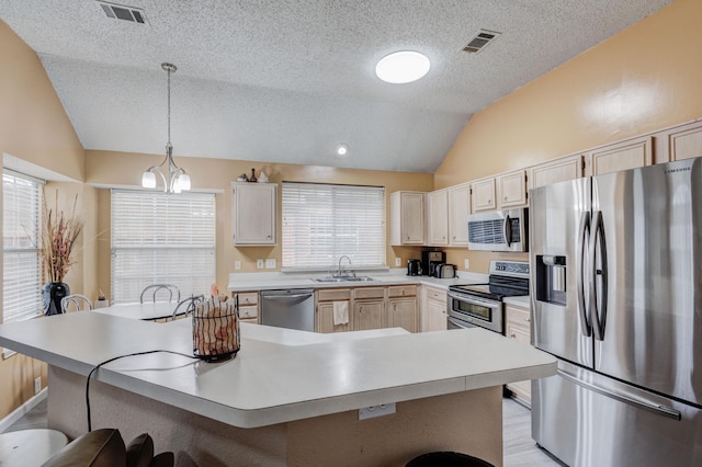 kitchen featuring lofted ceiling, sink, pendant lighting, stainless steel appliances, and a kitchen bar