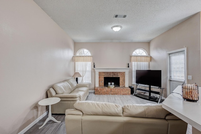 living room with hardwood / wood-style flooring, a fireplace, and a textured ceiling