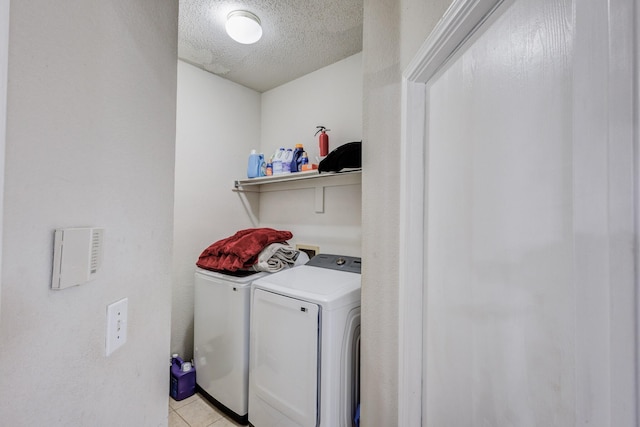 laundry room featuring washing machine and dryer, a textured ceiling, and light tile patterned floors