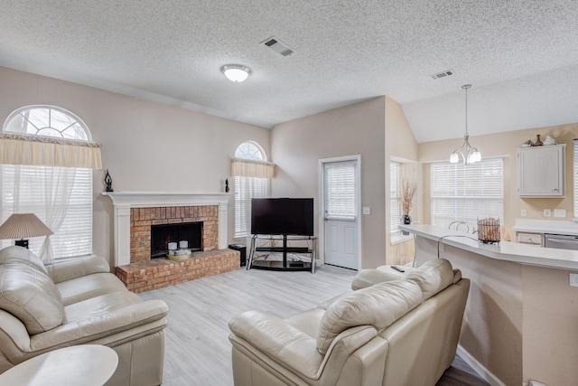 living room featuring a brick fireplace, vaulted ceiling, a textured ceiling, and light wood-type flooring