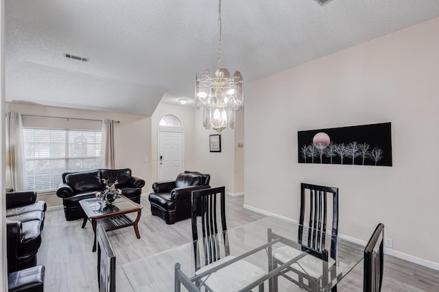 living room featuring a notable chandelier, wood-type flooring, and a textured ceiling