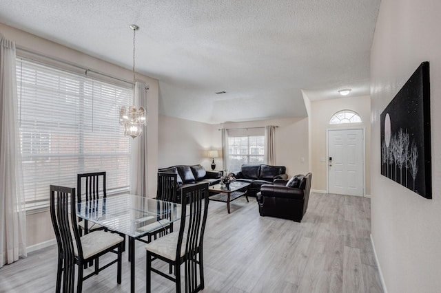 dining room featuring light hardwood / wood-style floors, a chandelier, and a textured ceiling