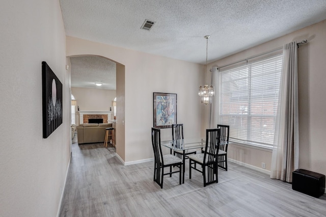 dining room featuring a textured ceiling, a chandelier, and light hardwood / wood-style flooring