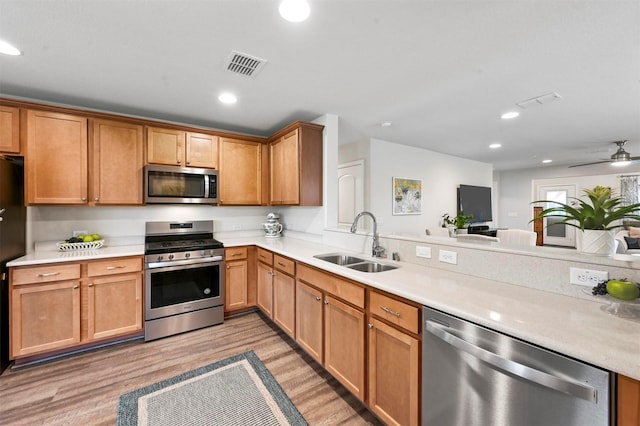 kitchen featuring sink, ceiling fan, appliances with stainless steel finishes, kitchen peninsula, and light wood-type flooring