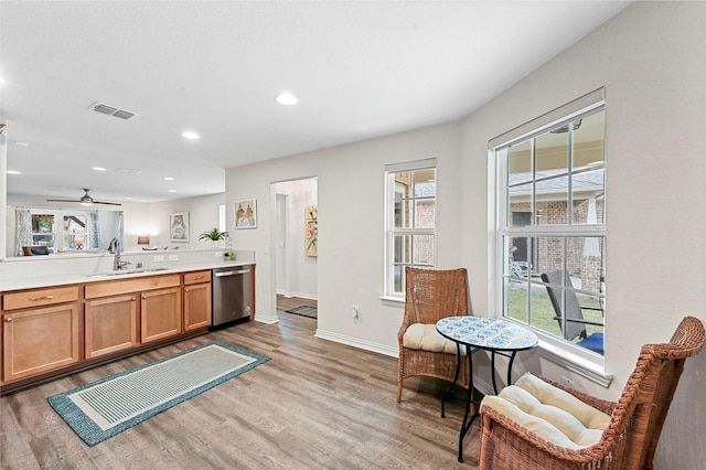 kitchen with dishwasher, sink, light wood-type flooring, and kitchen peninsula