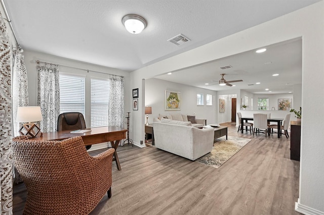 living room featuring a textured ceiling, ceiling fan, and light wood-type flooring