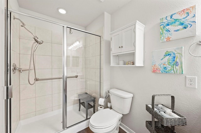 bathroom featuring a shower with door and toilet