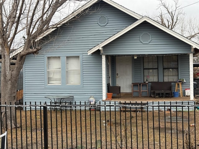 bungalow with a fenced front yard and covered porch