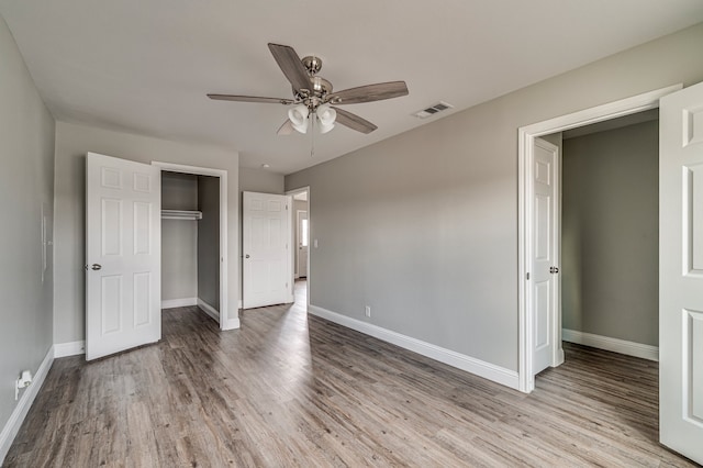 unfurnished bedroom featuring hardwood / wood-style floors, ceiling fan, and a closet