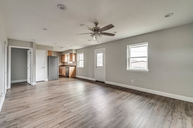 unfurnished living room featuring ceiling fan and light hardwood / wood-style floors