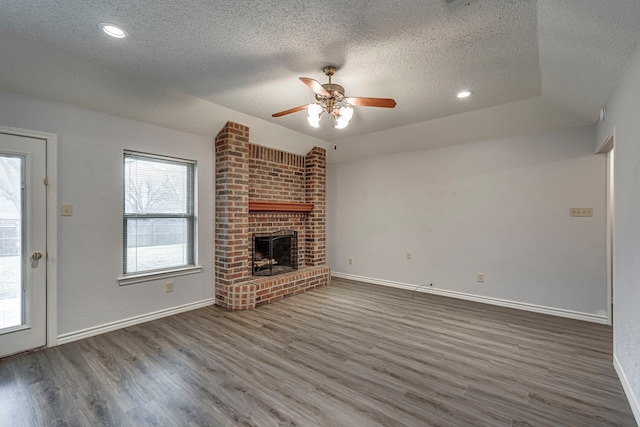 unfurnished living room with ceiling fan, dark wood-type flooring, a textured ceiling, and a fireplace