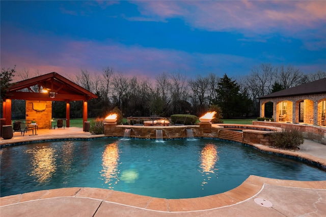 pool at dusk with a gazebo, pool water feature, an in ground hot tub, and a patio area