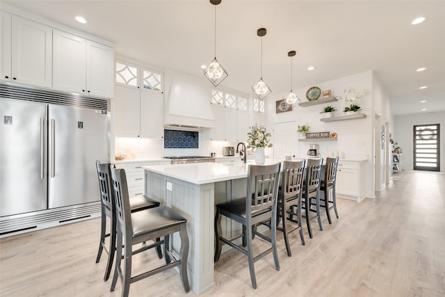 327 Lovers Ln, Terrell, TX 75160 - kitchen featuring decorative backsplash, light wood finished floors, built in appliances, and custom exhaust hood