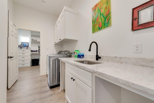 327 Lovers Ln, Terrell, TX 75160 - laundry room featuring a sink, separate washer and dryer, light wood-type flooring, and cabinet space
