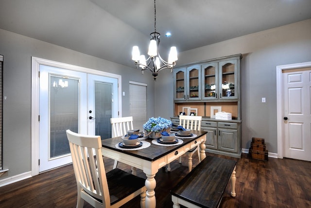 dining space with french doors, dark hardwood / wood-style flooring, a chandelier, and vaulted ceiling