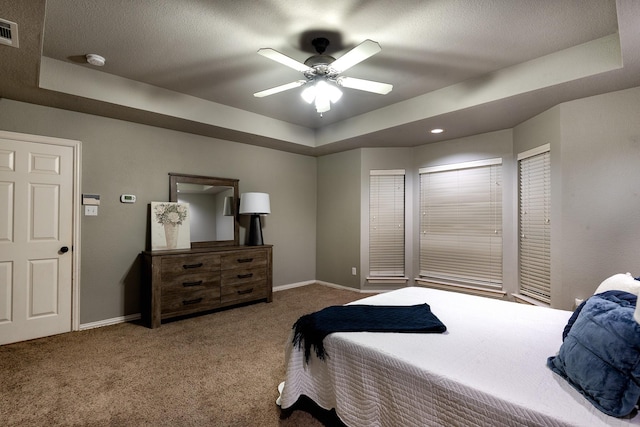 bedroom with a textured ceiling, carpet floors, a raised ceiling, and ceiling fan