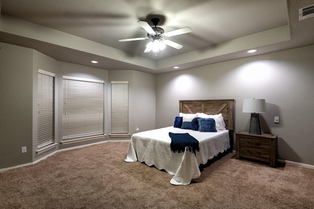 bedroom with ceiling fan, carpet flooring, and a tray ceiling