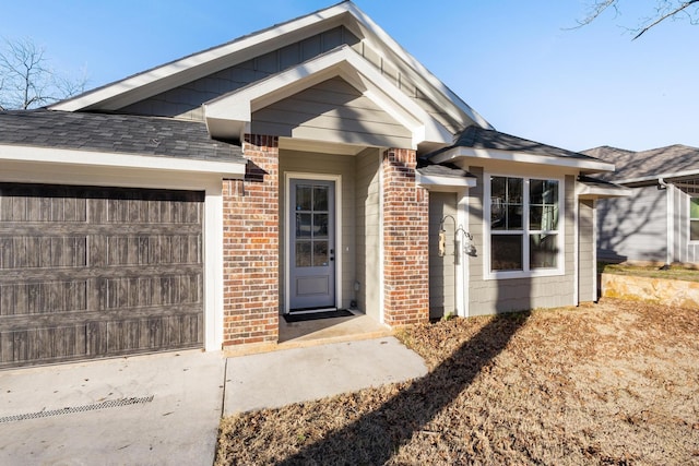 entrance to property featuring brick siding, board and batten siding, concrete driveway, roof with shingles, and an attached garage