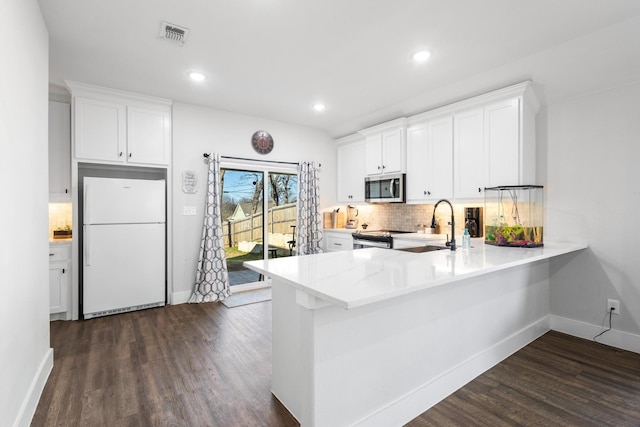 kitchen featuring tasteful backsplash, white cabinetry, sink, kitchen peninsula, and stainless steel appliances