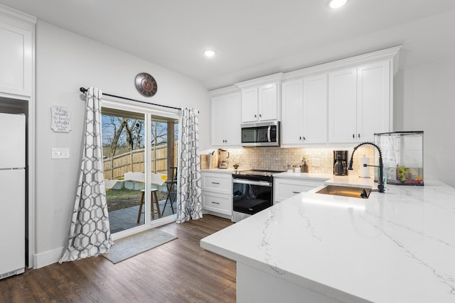 kitchen with sink, stainless steel appliances, white cabinets, dark hardwood / wood-style flooring, and decorative backsplash