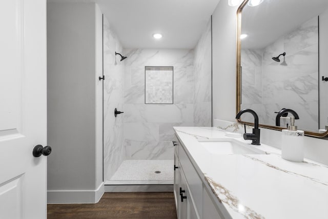 bathroom featuring hardwood / wood-style flooring, vanity, and a tile shower