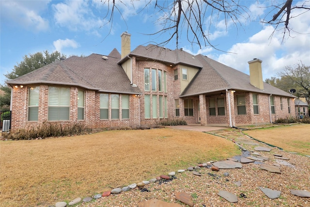 rear view of house with a lawn and a patio