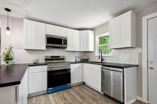 kitchen featuring white cabinetry, stainless steel appliances, decorative light fixtures, and sink