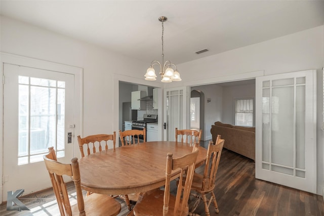 dining area featuring dark wood-type flooring and an inviting chandelier