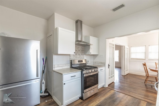 kitchen with white cabinetry, stainless steel appliances, light stone countertops, dark wood-type flooring, and wall chimney exhaust hood