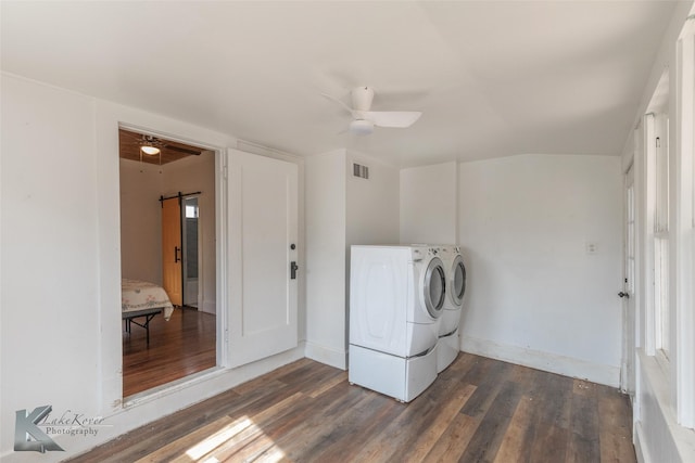 clothes washing area featuring a barn door, ceiling fan, separate washer and dryer, and dark hardwood / wood-style flooring