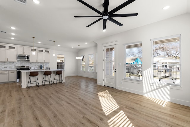 living room featuring ceiling fan with notable chandelier and light hardwood / wood-style floors