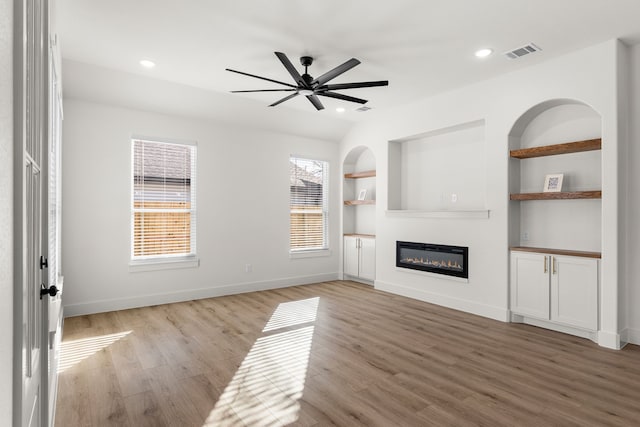 unfurnished living room featuring wood-type flooring, built in features, and ceiling fan