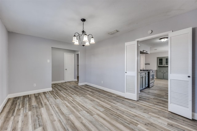 spare room featuring a chandelier and light hardwood / wood-style floors