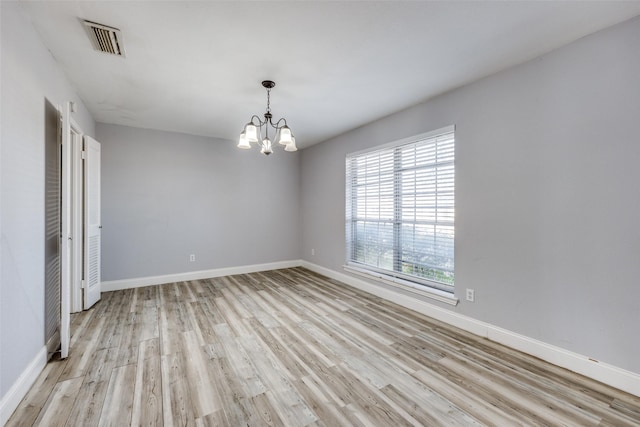 unfurnished room with a notable chandelier and light hardwood / wood-style flooring