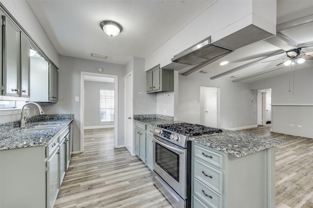 kitchen featuring range hood, sink, gray cabinetry, stainless steel gas range oven, and light hardwood / wood-style flooring