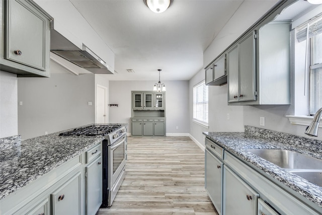 kitchen with gray cabinets, pendant lighting, sink, gas range, and light hardwood / wood-style flooring