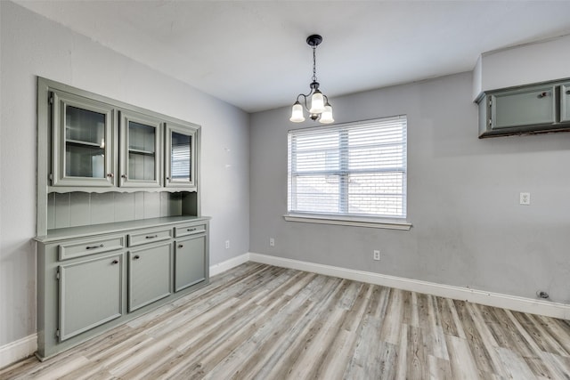 unfurnished dining area with a chandelier and light wood-type flooring