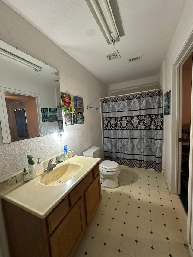 bathroom with vanity, toilet, curtained shower, and a textured ceiling