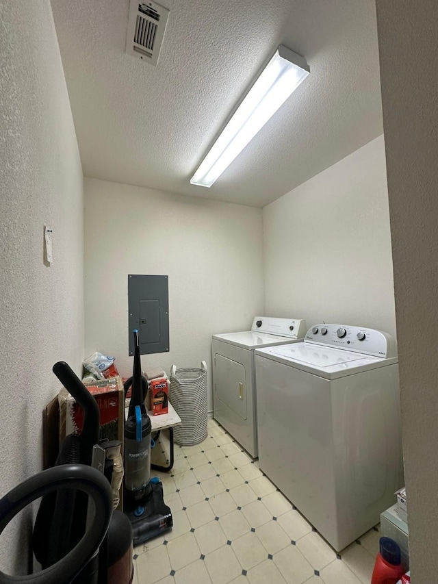 clothes washing area featuring electric panel, washer and dryer, and a textured ceiling