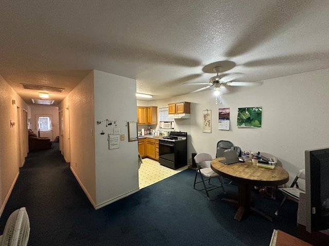 kitchen featuring ceiling fan, range with gas stovetop, light colored carpet, and a textured ceiling