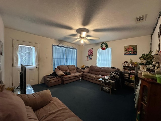 living room with dark colored carpet, plenty of natural light, ceiling fan, and a textured ceiling