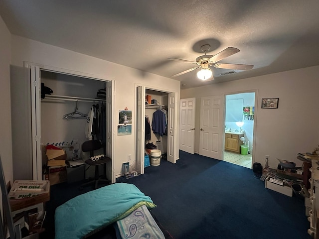 carpeted bedroom featuring multiple closets, a textured ceiling, and ceiling fan