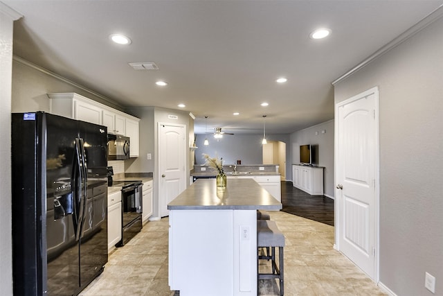 kitchen featuring sink, a kitchen bar, hanging light fixtures, a center island, and black appliances