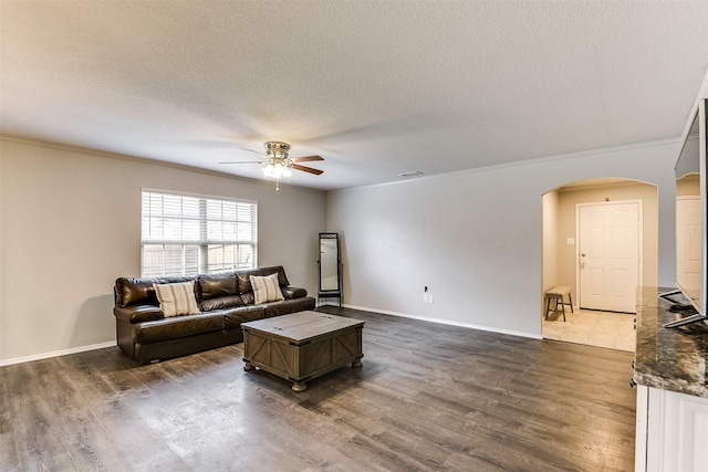 living room with crown molding, dark wood-type flooring, a textured ceiling, and ceiling fan