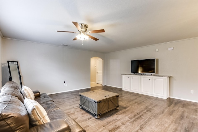 living room featuring ceiling fan, ornamental molding, and light wood-type flooring