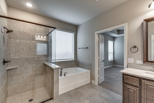 bathroom with tile patterned flooring, vanity, and plus walk in shower